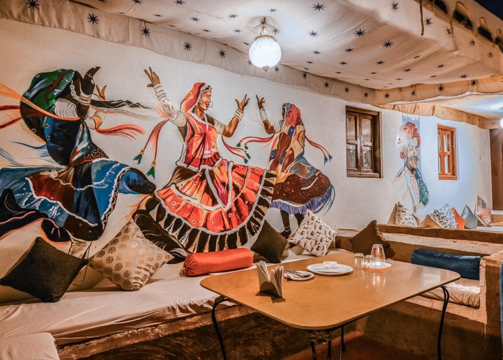 Hand-painted Kalbeliya dancer mural on the dining lounge wall at Explore Overnight Desert Camp Jaisalmer