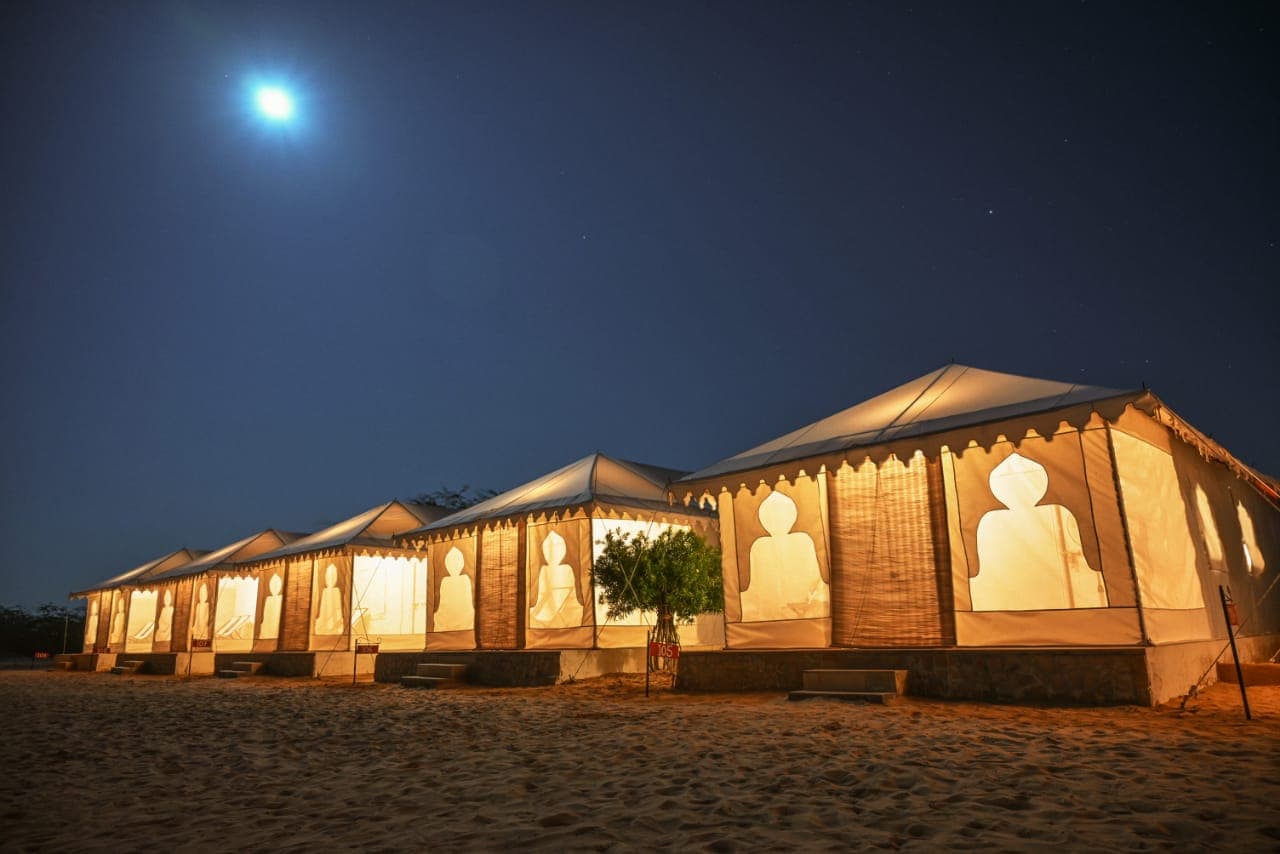 Royal Swiss Tents glowing under a moonlit Thar sky